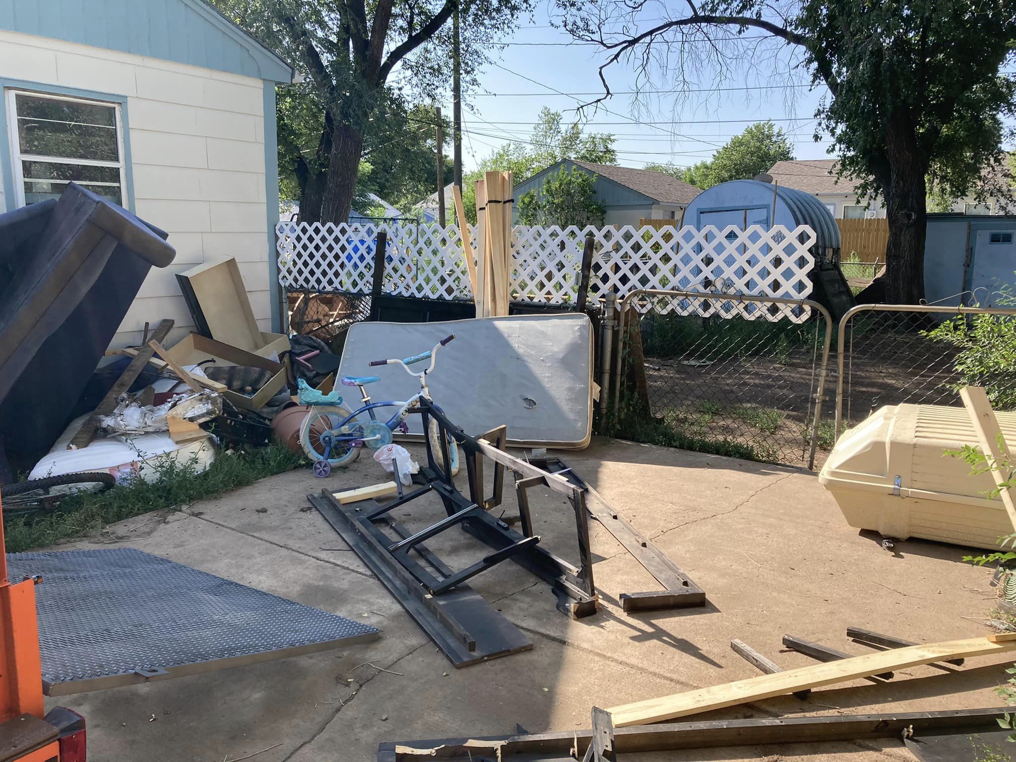 Backyard cluttered with junk piles and fencing before removal